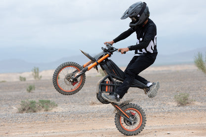 Child riding GT54 electric mini motorbike performing a wheelie on a dirt trail outdoors