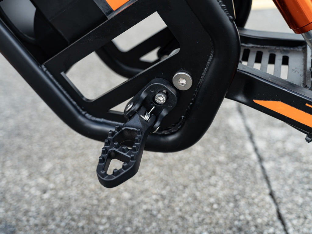 Close-up of GT54 electric mini motorbike foot pedal and frame in black and orange colors